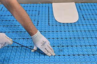 Prodeso floor heating membrane with ComfortTile floor heating cable being installed.